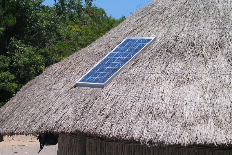 A solar panel on a grass thatched house